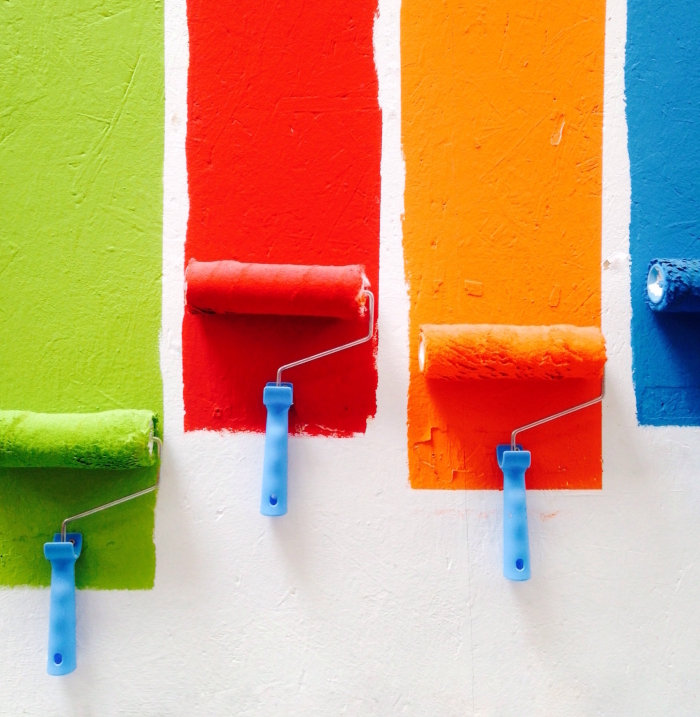 Four lines of paint drawn on a roller, in green, red, orange and blue